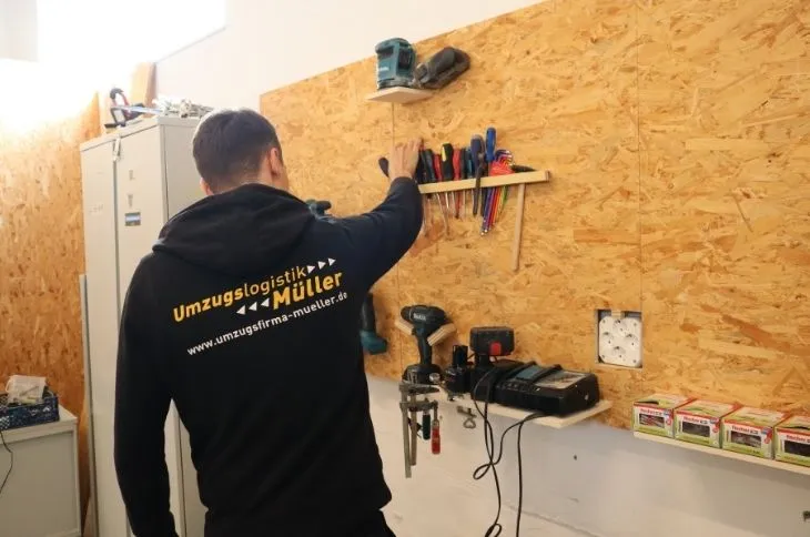 umzugshelfer ordnet werkzeug an werkbank in werkstatt